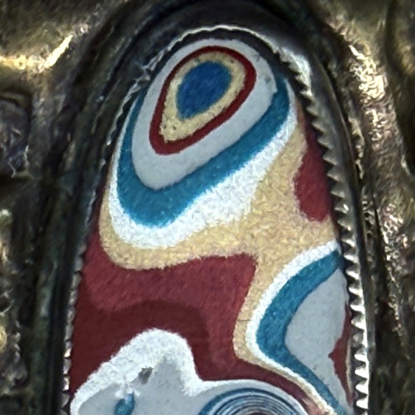 Macro of the Detroit-paint fordite grille badge on the brass box
