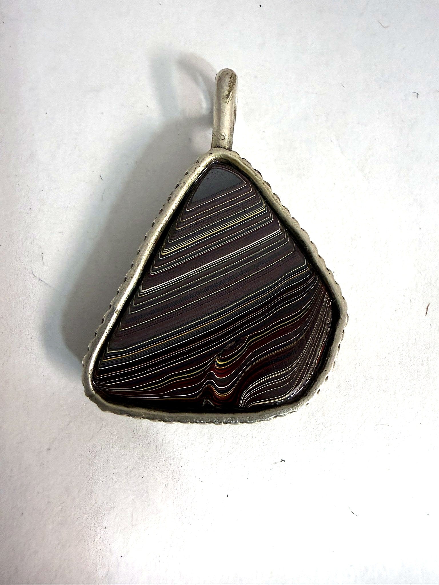 Reversible striped face of the fordite triangle pendant — parallel bands of layered auto paint