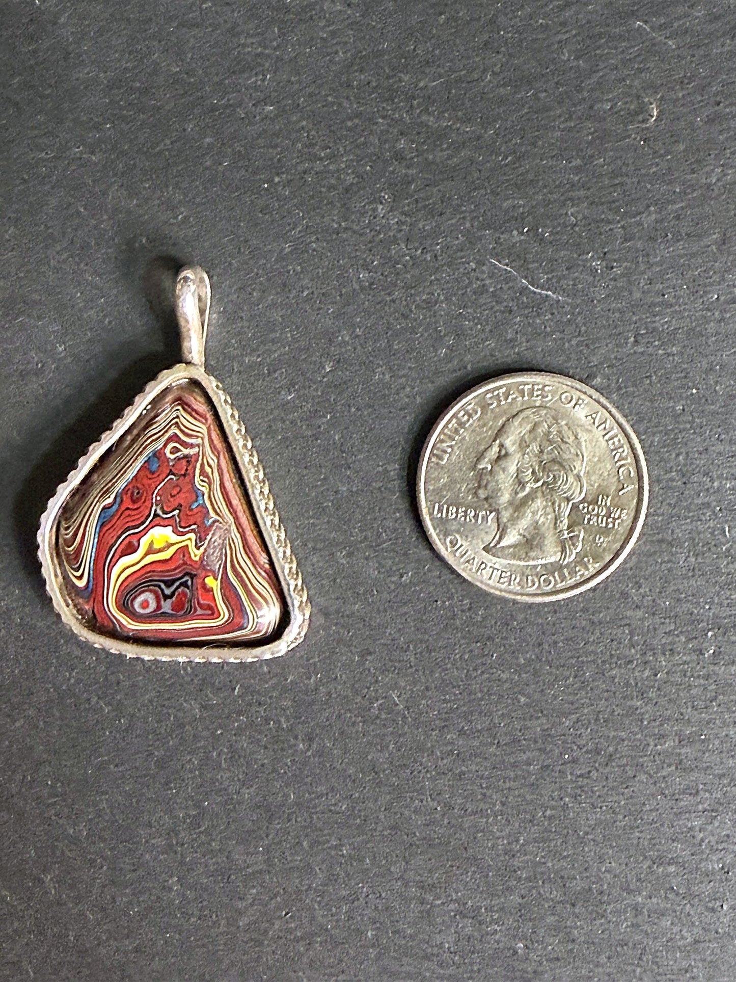 Reversible fordite Detroit agate triangle pendant, bullseye face — concentric rings of red, gold, blue and white auto paint in a twisted rope sterling bezel
