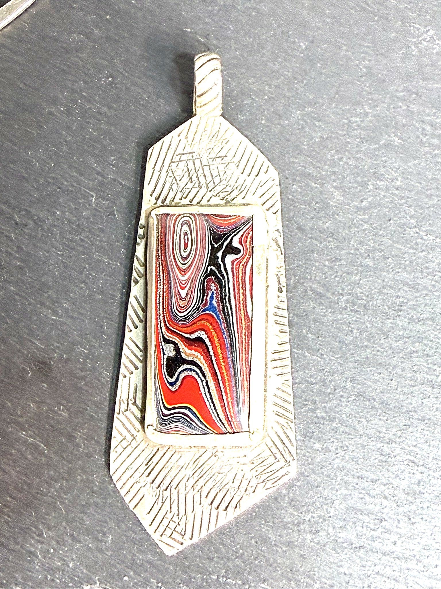 Fordite stamped-bar pendant styled on slate