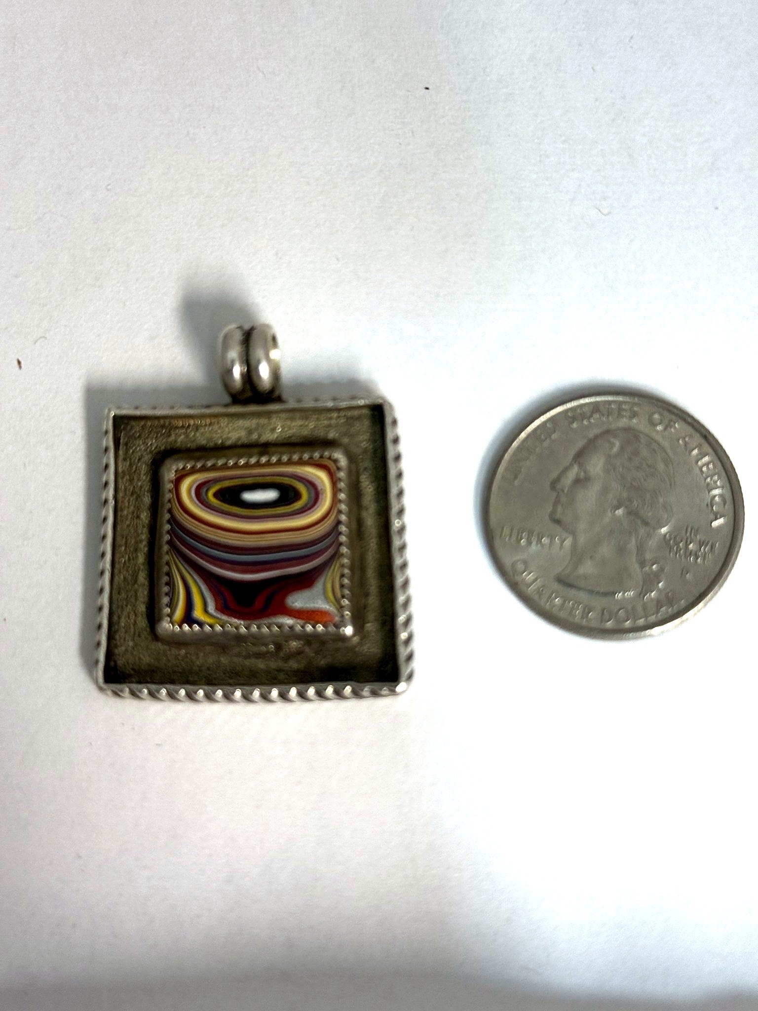 Fordite square pendant shown beside a US quarter for scale