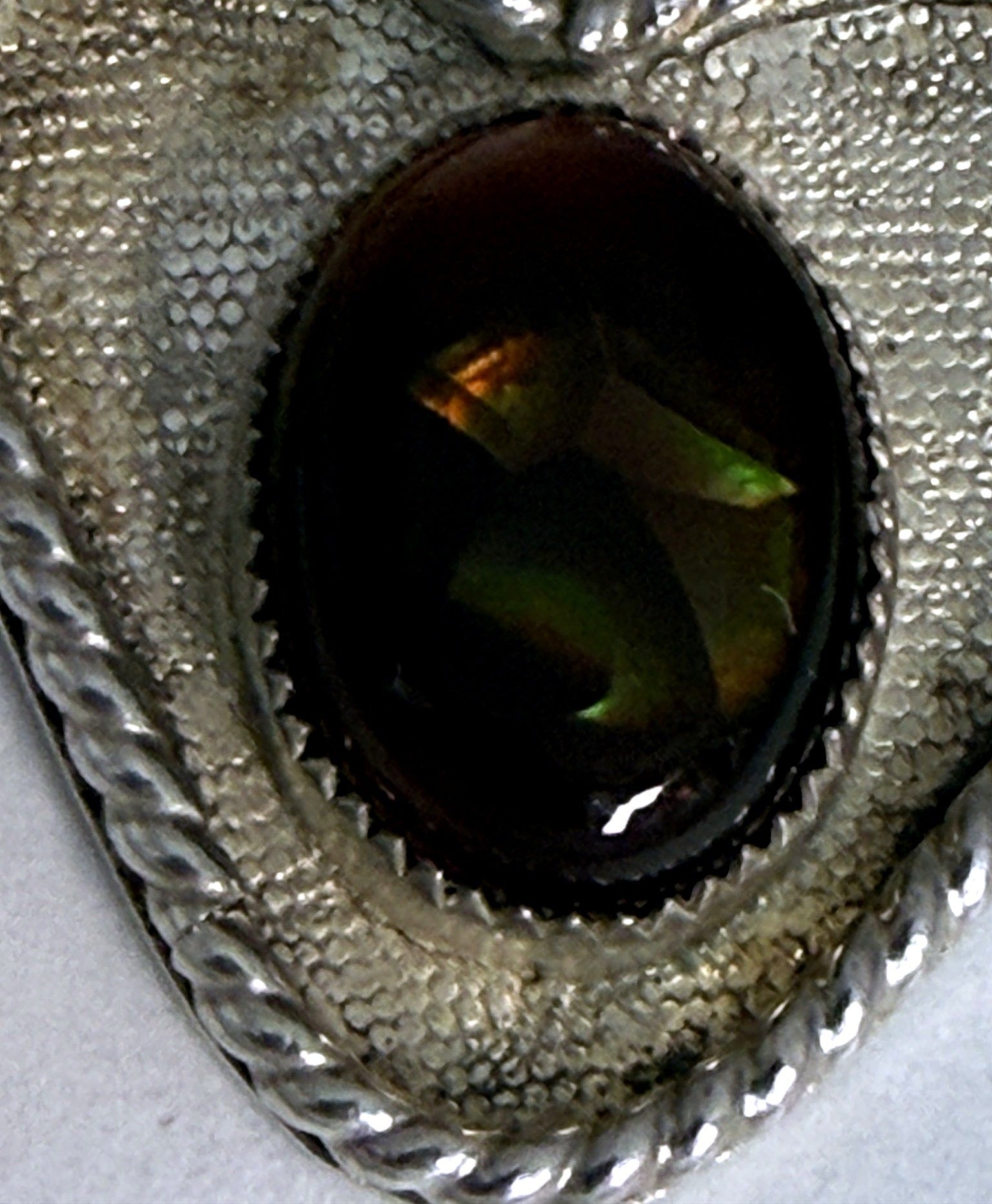 Macro of the fire agate cabochon showing flashes of green, gold and orange fire