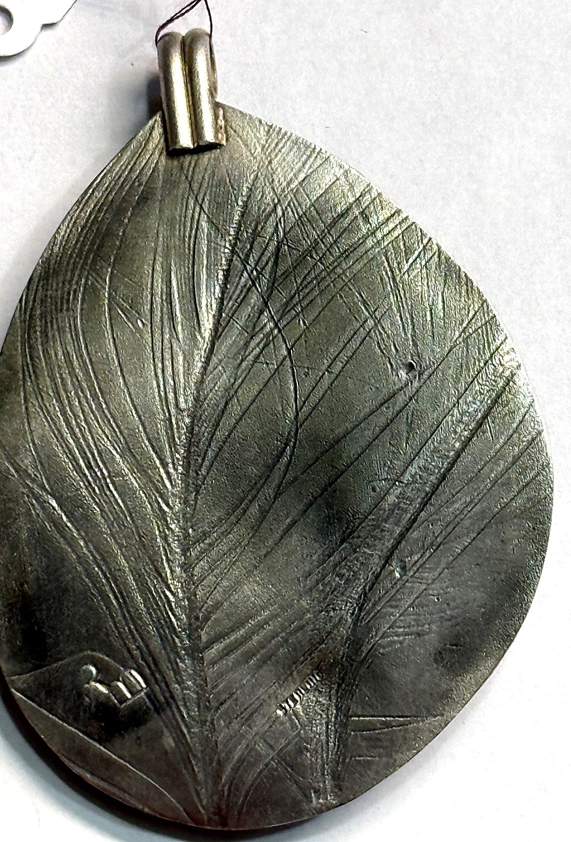 Reversible back of the teardrop pendant — hand-formed leaf impression in sterling silver